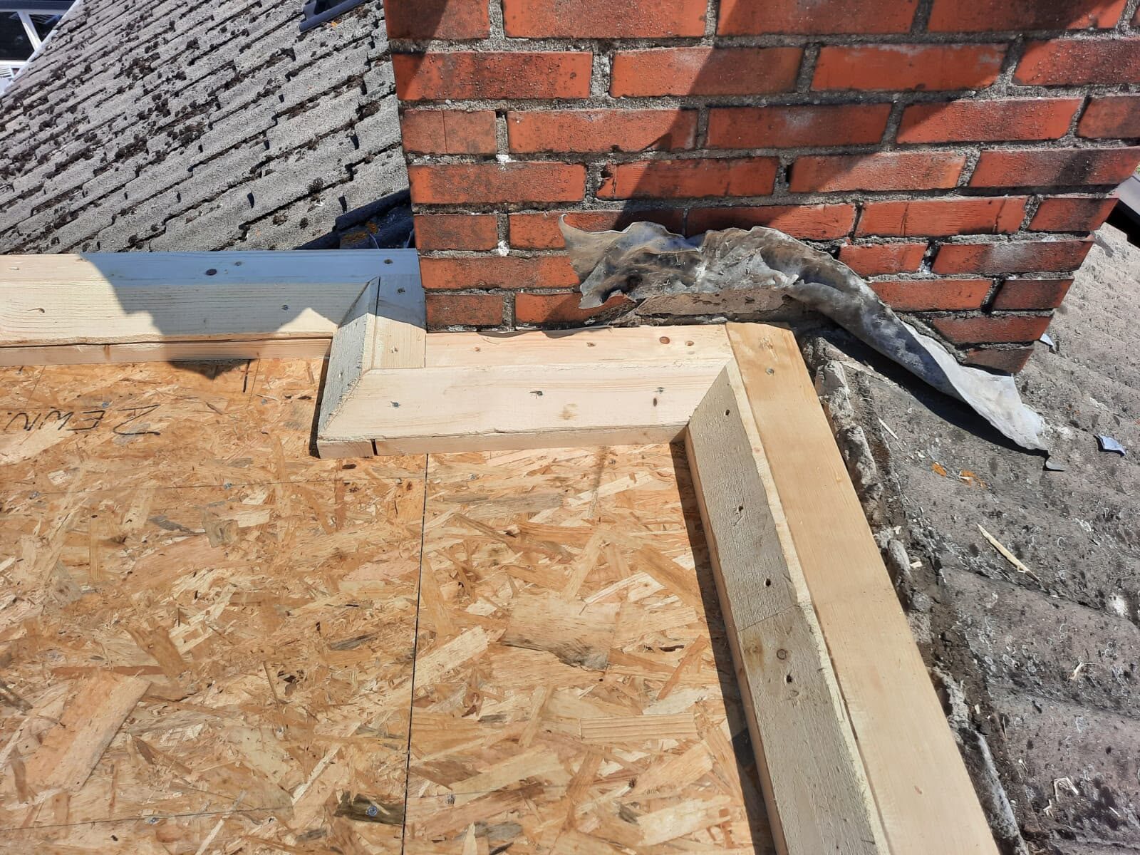 Houten dakconstructie met OSB-plaat en loodaansluiting bij schoorsteen door Klus Expert Breda